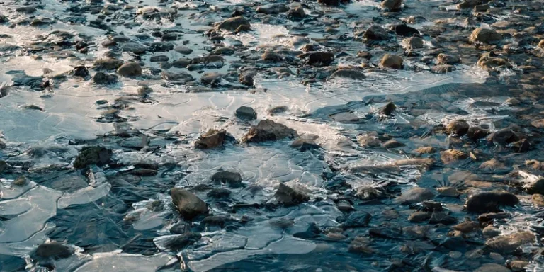 Detailed view of a frozen stream with ice-covered stones creating a textured surface