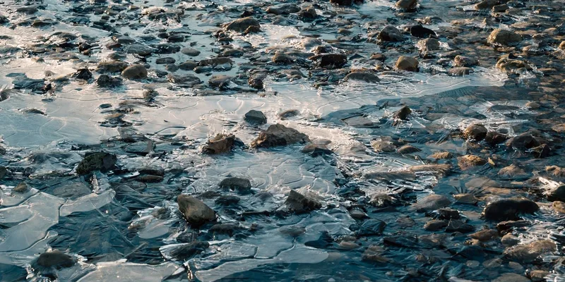 Detailed view of a frozen stream with ice-covered stones creating a textured surface