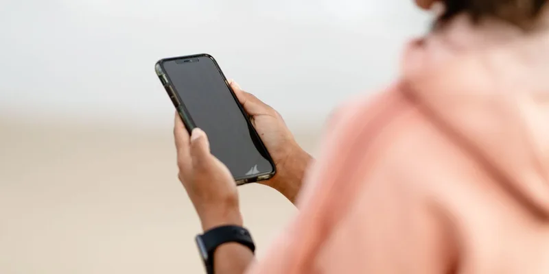 Close-up of a person using a smartphone outdoors, focusing on modern technology